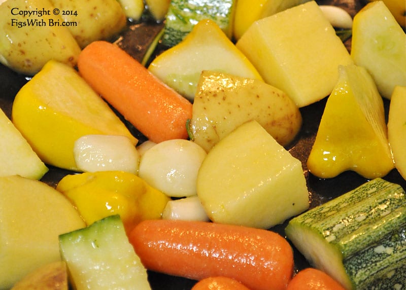 Striped Zucchini, yellow Pattypan Squash & Potatoes, bright orange Carrots, and Garlic coated with salted virgin Olive Oil ready for roasting.